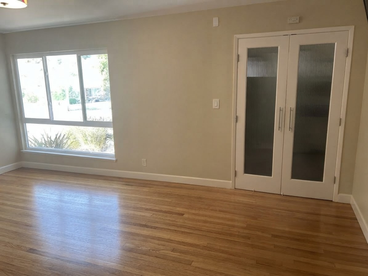 Front formal living room with hardwood floors, a window, and white double doors with frosted glass