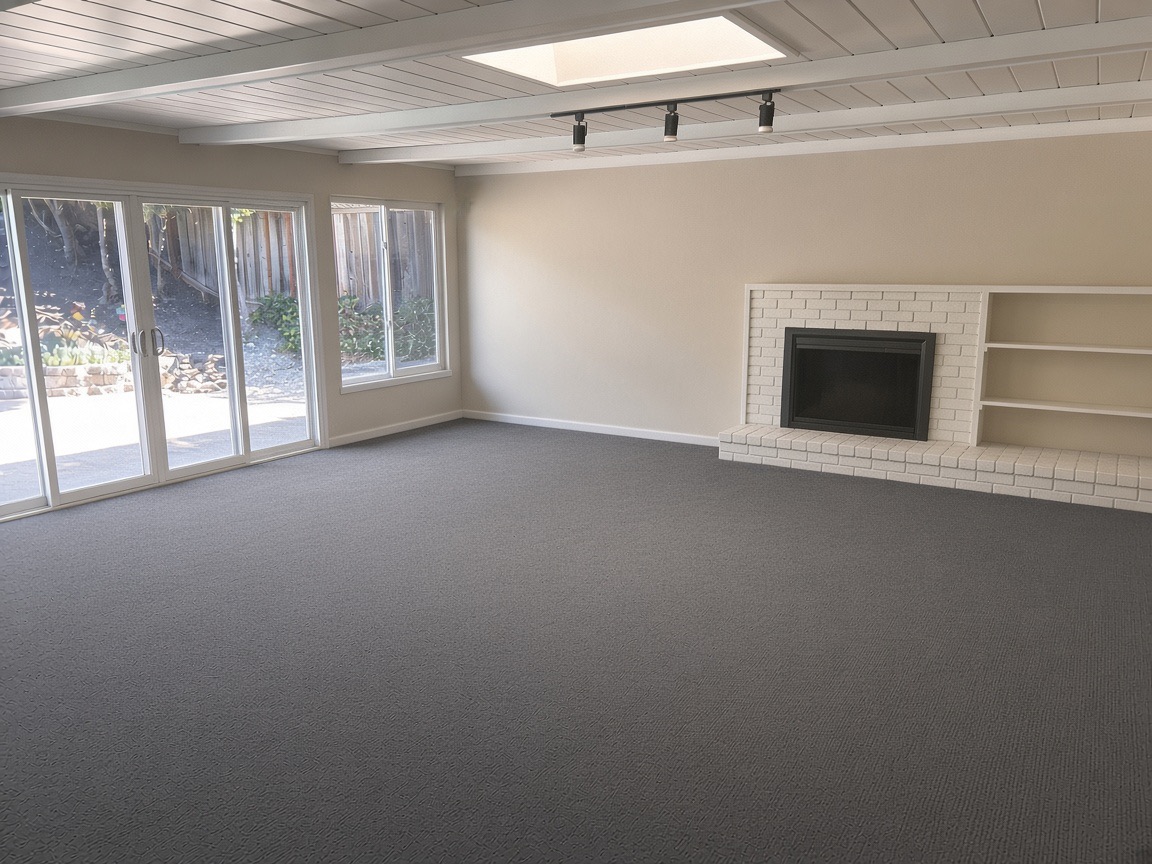 Empty living room with gray carpet, a white brick fireplace, built-in shelves, and sliding glass doors