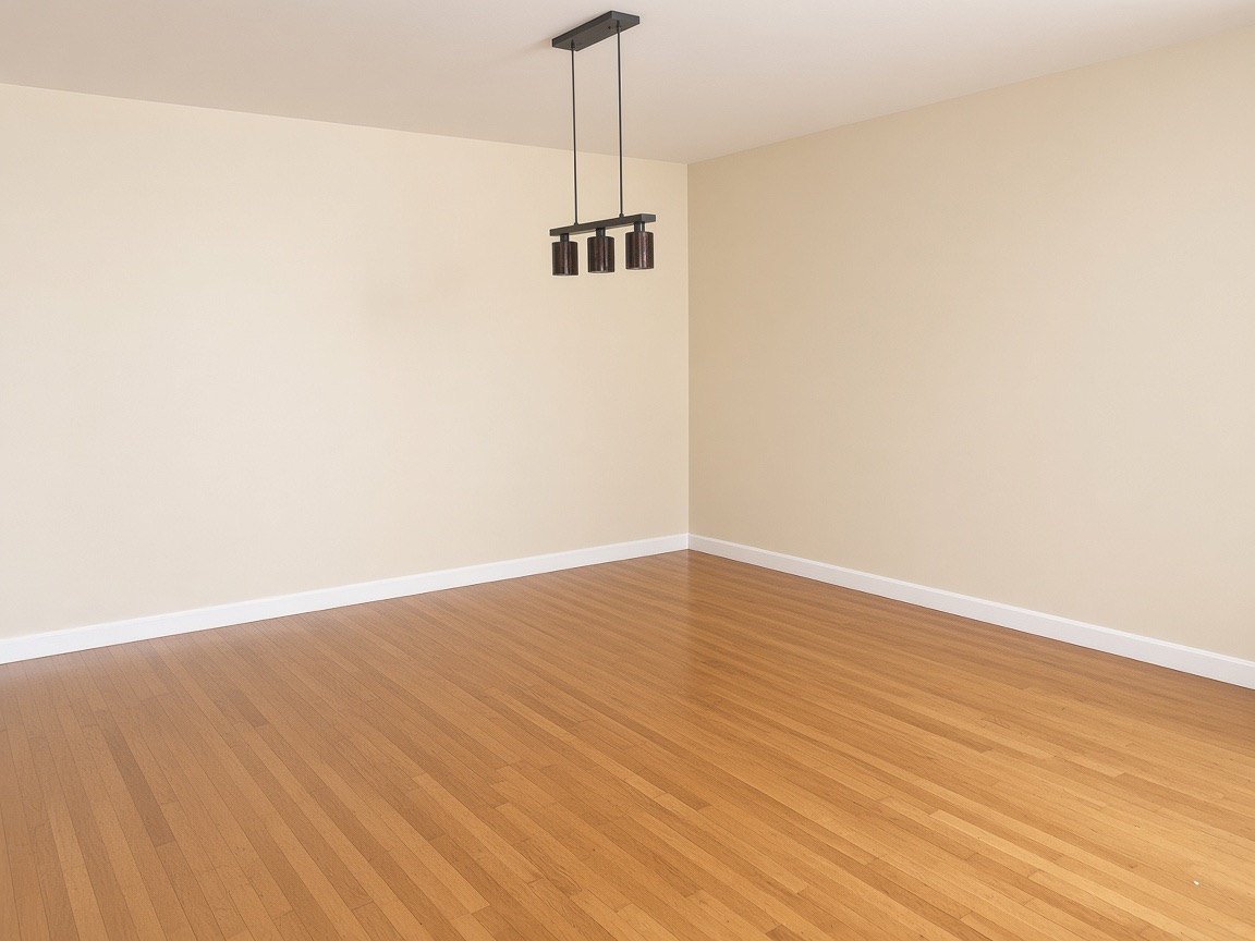 Empty dining room with honey-colored hardwood floors and a dark three-light pendant