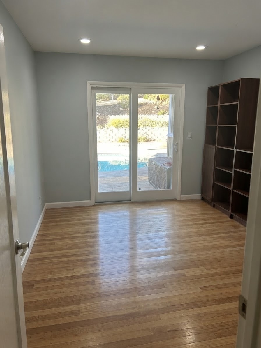 Bedroom with hardwood floors, a bookcase, and a sliding door opening toward the pool