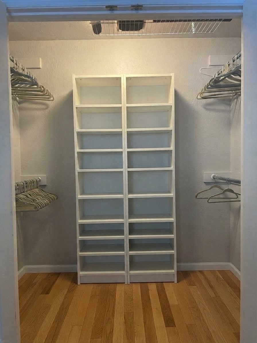 Walk-in closet with a white shoe shelf in the center and hanging rods on both sides