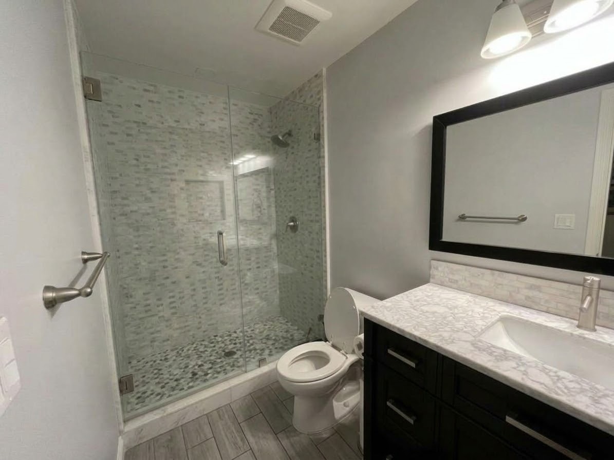 Bathroom with a glass walk-in shower, marble vanity, and toilet