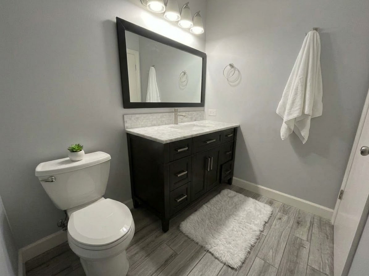 Bathroom vanity with a dark wood cabinet, marble counter, and framed mirror
