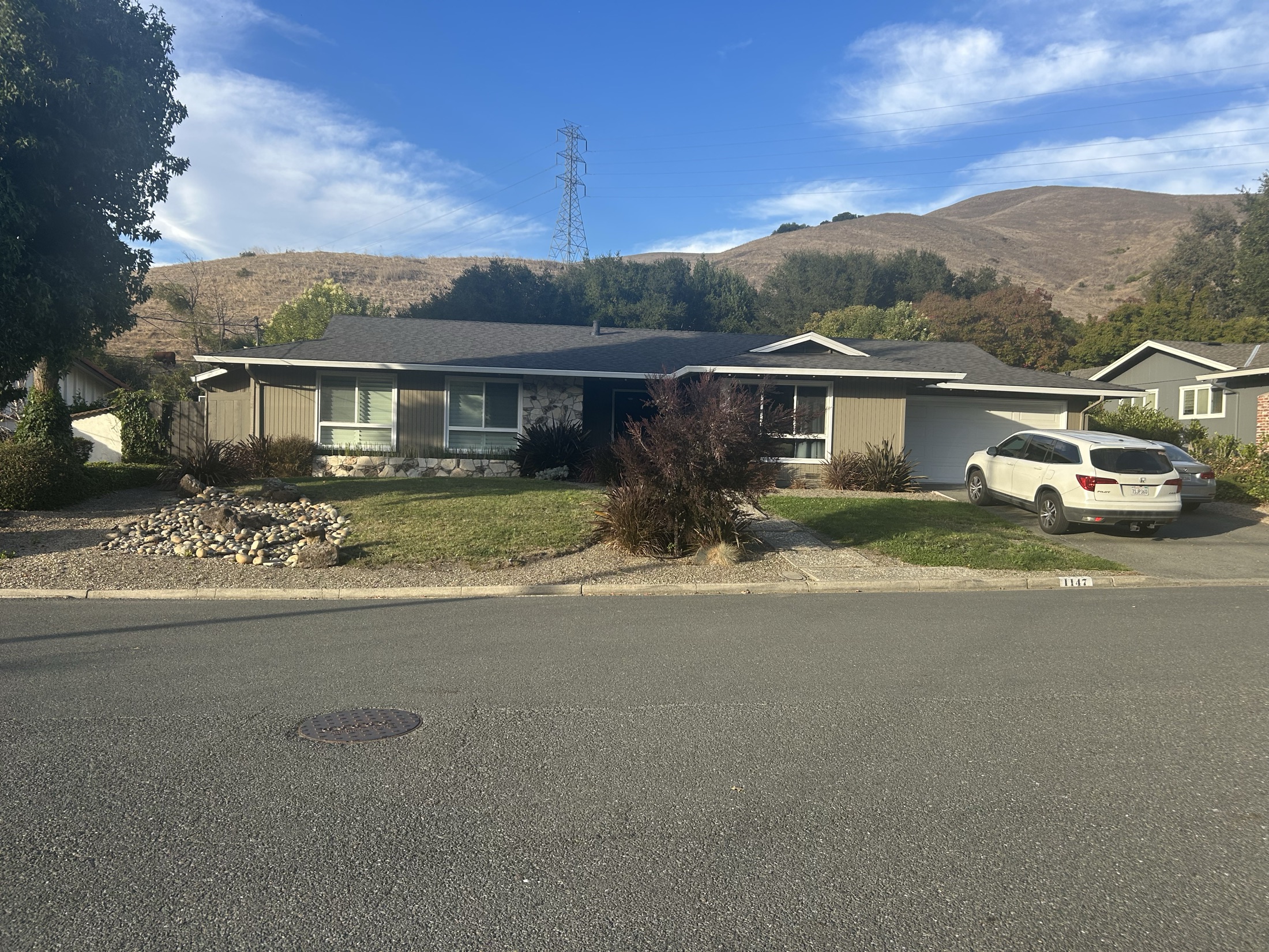 Single-story house at  Sanders Drive, with a lawn, garage, and hills behind it