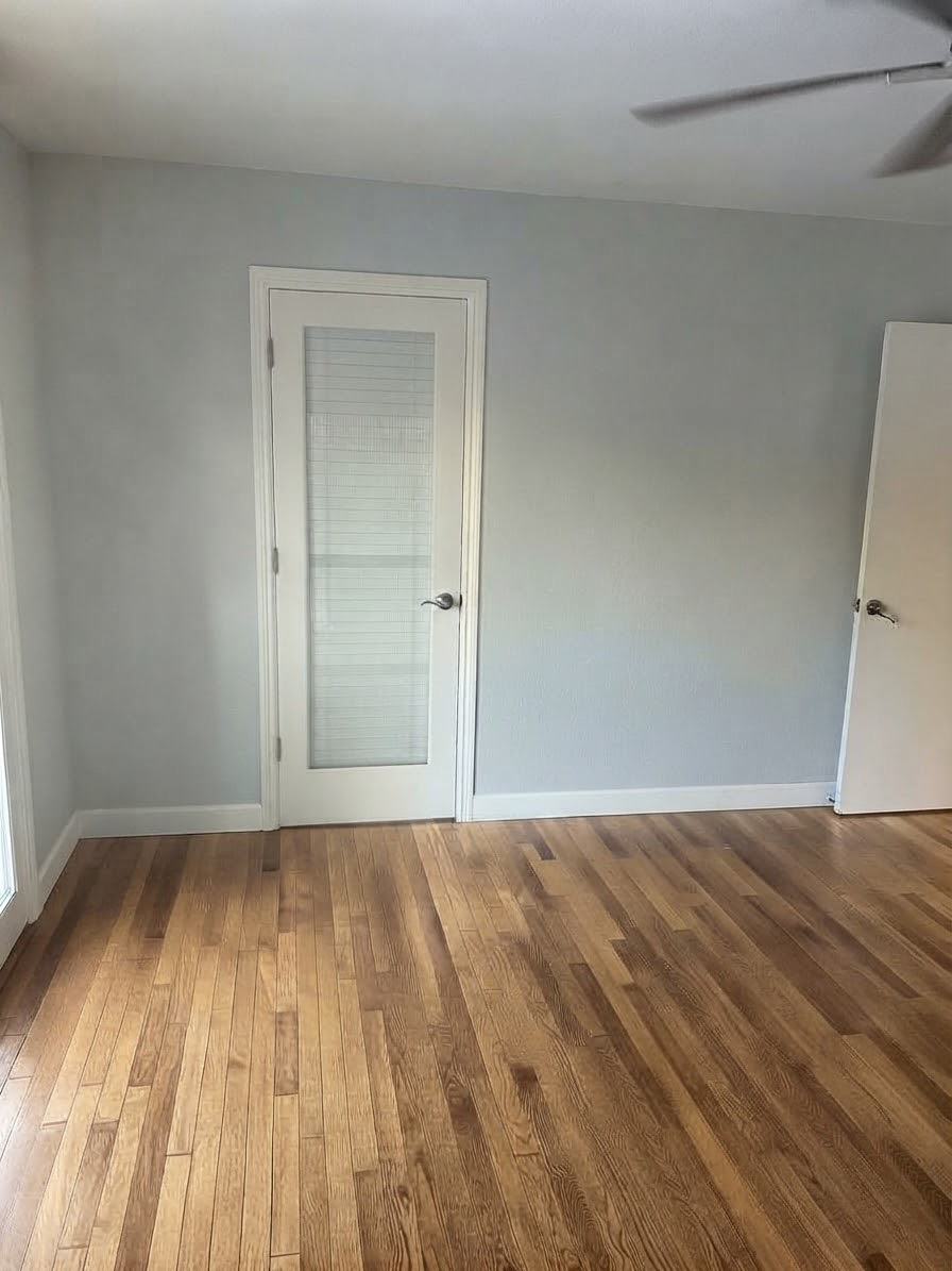 Bedroom with light blue walls, hardwood floors, a ceiling fan, and a white closet door